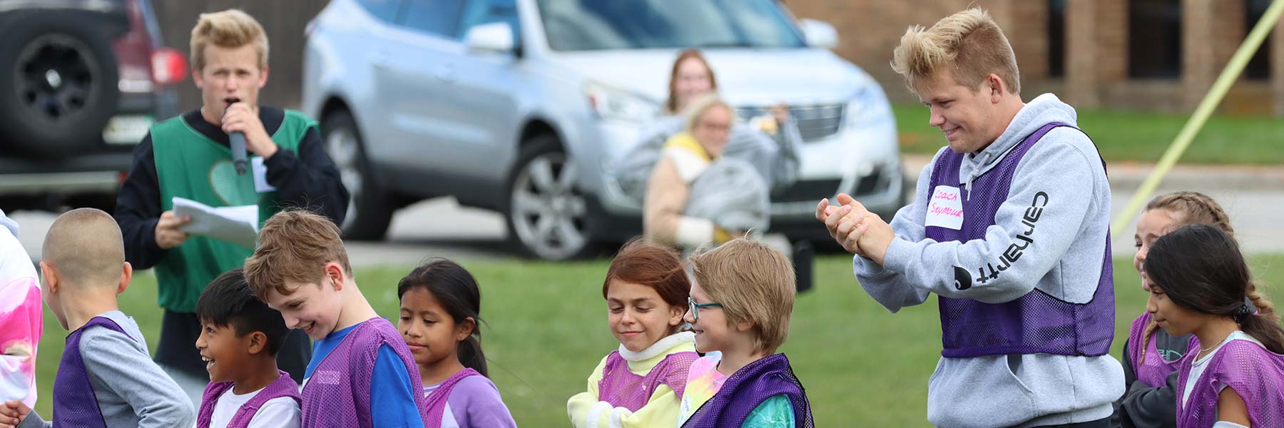 A male student coaching soccer with young children